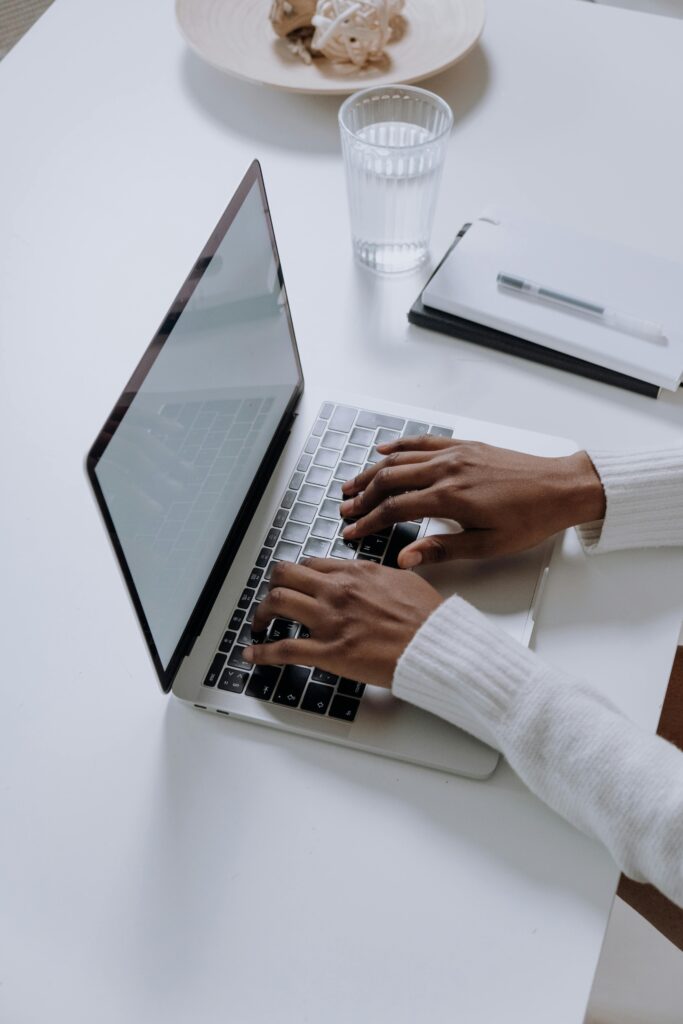 A woman typing on a laptop at a minimalist, modern home office desk, showcasing productivity.